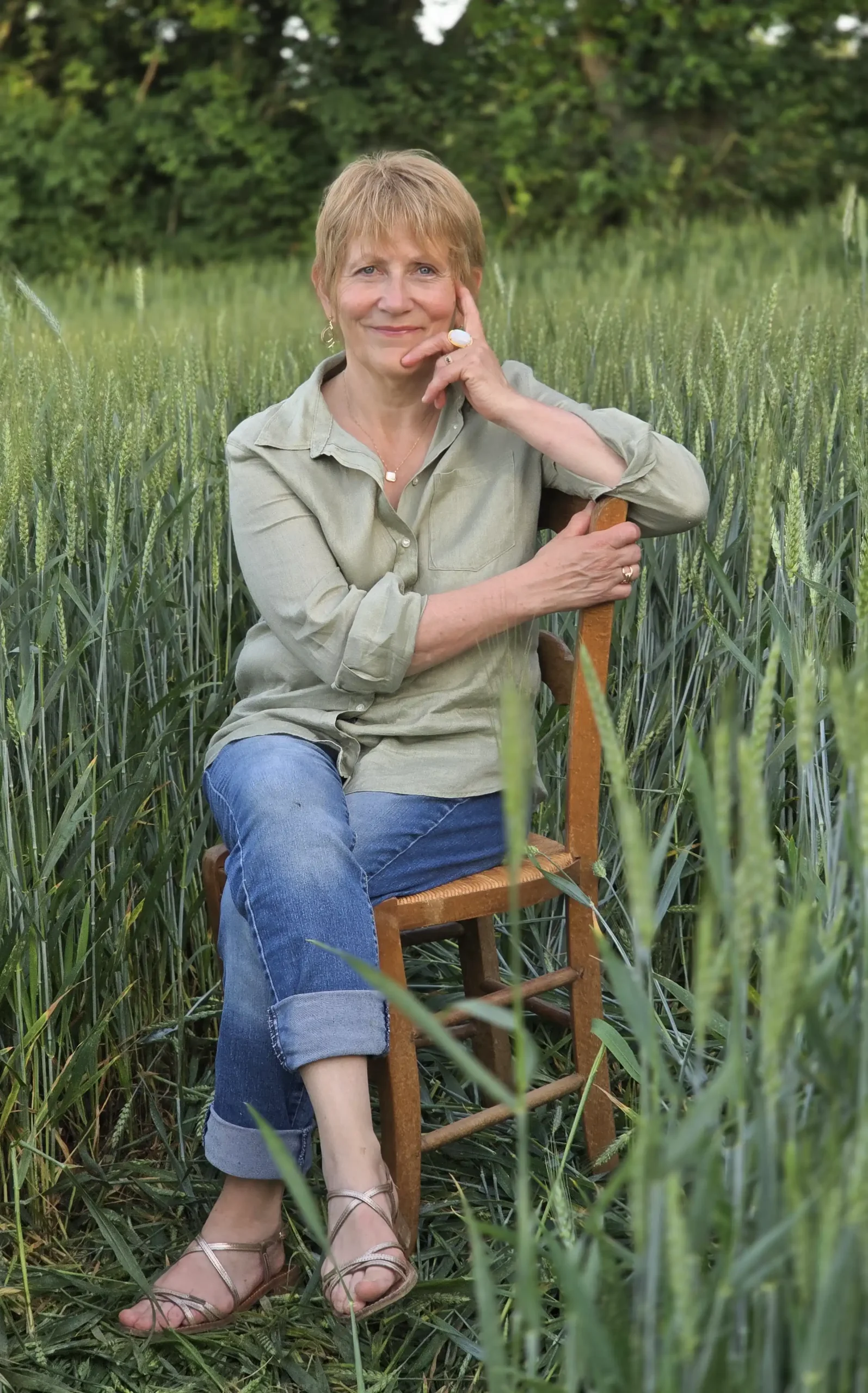 Femme blonde assise sur une chaise en bois dans un champ de blé